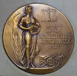 Médaille représentant une femme, debout, un parchemin à la main.