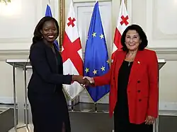 Photographie en couleurs de deux femmes se serrant la main en souriant