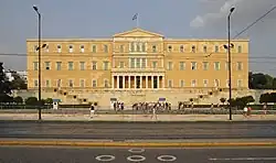 Photographie en couleurs montrant un bâtiment jaune à quatre étages bâti sur une sorte de terrasse.