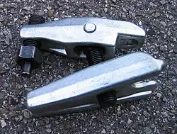 Une sorte de grosse pince à linge en métal articulée autour d'une longue vis.