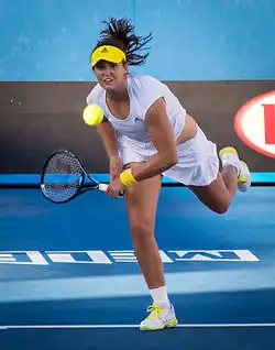 Une joueuse de tennis terminant son geste de service.