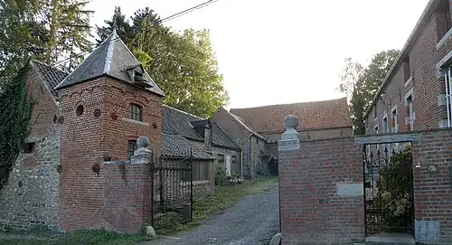 Ferme typique, sise rue Ghislain Luciez no&nbsp;1, avec sa tour-colombier à gauche du portail d’entrée et son corps de logis à droite.