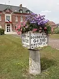Ancienne borne Michelin fleurie devant la mairie.