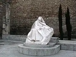 Statue de marbre blanc, posée dans une cour, représentant une religieuse assise.