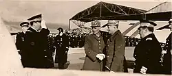 Deux généraux se serrent la main, encadrés d'officiers de l'Armée de l'air, sur une base aérienne.