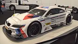 Voiture blanche, avec certaines parties rouges et bleues, vue de trois-quarts.