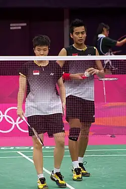 Deux joueurs de badminton se tiennent debout derrière le filet.