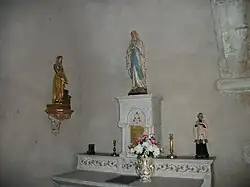 Autel et tabernacle surmonté d'une statue de Notre-Dame de Lourdes avec à gauche la statue de sainte Germaine et à droite la statue de saint Jean-Marie Vianney