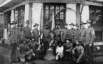 Groupe d'hommes, un garçon et une cloche d'église sur le sol