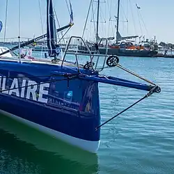 De trois quarts face, avant d'un voilier bleu. L'étrave est droite.