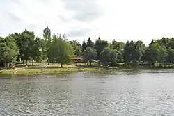 Le lac de barrage au premier plan et la zone de baignade de la base de loisirs
