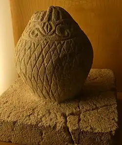 Base surmontée d'une pomme de pin.