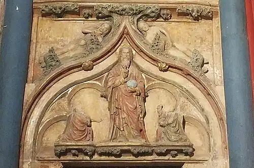 En partant du bas vers le haut, Dieu le Père tenant l'univers est accompagné de deux anges agenouillés. Ces trois personnages sont surmontés par Adam et Ève se couvrant les parties intimes.