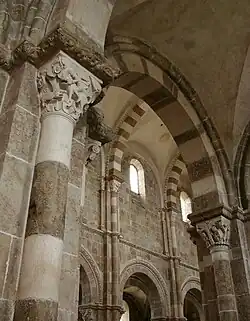 Les parties hautes de la nef vues depuis le collatéral sud : au premier plan, la 5e&nbsp;pile côté sud dont le chapiteau représente David et le lion, en arrière-plan, les fenêtres hautes du côté nord de la nef surmontant les arcades donnant sur le collatéral nord.