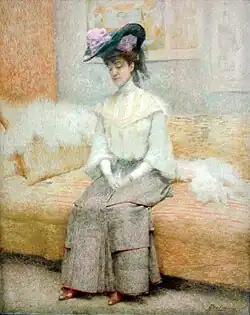 Peinture représentant une femme élégante assise sur un canapé jaune orné de coussins et d'une étole en fourrure blanche. Elle porte une robe longue grise avec des détails rouges, un chemisier blanc à col haut et des gants. Son chapeau noir décoré de fleurs violettes et de voiles ajoute une touche sophistiquée à sa tenue. Son expression est paisible, les yeux baissés et les mains jointes sur ses genoux. L'arrière-plan est composé de tons pastel et de formes floues, renforçant l'atmosphère douce et feutrée de la scène.