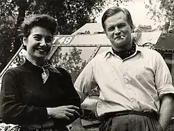 Photographie noir et blanc d'une femme et d'un homme devant une voiture.