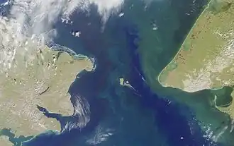 Photo satellite du détroit de Béring, avec le cap Dejnev (Russie) en haut à gauche, le cap Prince-de-Galles (Alaska) à droite et les îles Diomède au centre.
