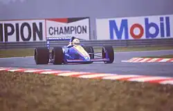 Photo d'une monoplace blanche et bleue sur une piste mouillée