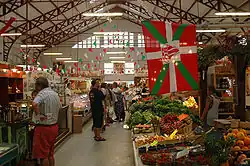Vue d'étals de commerçants dans des halles couvertes.