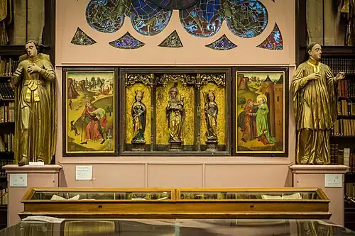 Retable avec la caisse centrale à décor sculpté et deux volets à décor peint. La huche est divisée en trois champs par des colonnettes à pinacles, reliées par des gâbles à rinceaux ajourés.