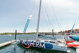 Vu de côté, voilier bleu sombre et bleu clair amarré au ponton.