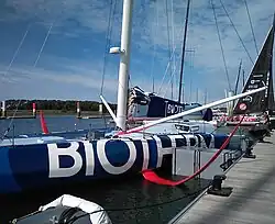 Plan rapproché sur les foils rouges d'un voilier bleu sombre et bleu clair amarré au ponton.