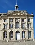 Palais de la Bourse à Bordeaux (1742-1749), avec des éléments caractéristiques du style rocaille : mascarons, ferronnerie à volutes, fenêtres en arc surbaissé avec agrafe.