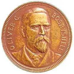 Médaille représentant un homme barbu, aux cheveux courts et portant des lunettes. Sur la gauche l'inscription OLIVER C. et sur la droite BOSBYSHELL.