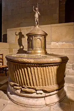 Cuve baptismale (12e&nbsp;siècle) couronnée d'une statuette de Jean-Baptiste (19e&nbsp;siècle), dans la collégiale Saint-Martin.
