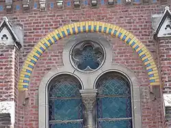 Un des arcs de plein-cintre de briques colorées, au dessus d'une fenêtre géminée.