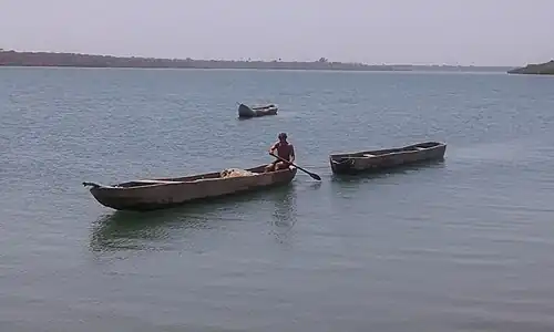 Photographie d'une pirogue en remorquant une autre dans un bras de mer.