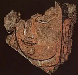 Détail d'une tête du Bouddha 21B. Registre haut du sanctuaire B en bois et enduits peints, vallée de la Keriya. Début du IIIe&nbsp;siècle. Musée provincial, Ürümqi.