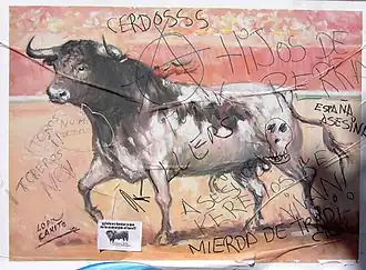 photographie en couleur montrant l'image peinte d'un taureau issu d'une affiche de corrida, recouverte de graffitis