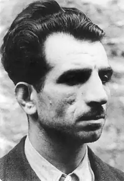 Portrait en noir et blanc d'un homme moustachu vêtu d'un costume.