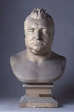 Photographie d'un buste, en marbre blanc, d'un homme corpulent, aux cheveux relevés.