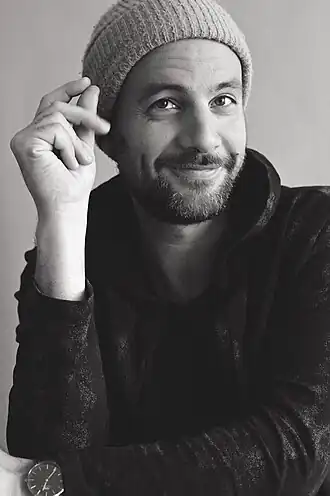 photo noir et blanc d'un homme, barbu et chauve, assis au piano