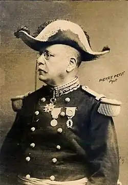 Photographie monochrome d'un homme assis, de profil, portant une tenue de général et un bicorne.