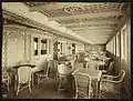 Le Café parisien du Titanic et ses fauteuils en rotin. Acajou, linoleum, staff et rotin (en partie fibres et bois coloniaux) font partie de la décoration des ponts supérieurs.
