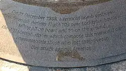 Photo agrandie de la base du monument, avec des inscriptions noires sur fond gris.