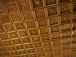 Photographie en couleurs d'un plafond à caissons doré.