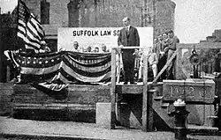 Coolidge se tient sur une estrade décorée par des drapeaux américains.