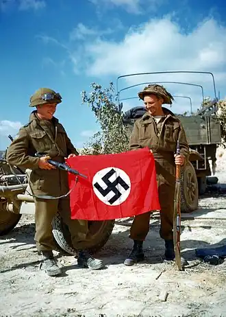 Canadian soldiers during Operation Overlord showing a captured Nazi flag as a war trophy outside Hautmesnil, France in August 1944.Photo: National Archives of Canada
