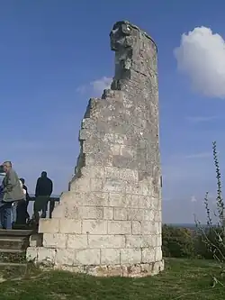 Photographie en couleurs d'un ancien moulin dont il ne reste qu'une portion de mur courbe.
