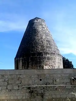 Photographie en couleurs d'une petite tour terminée par un cône en pierre.