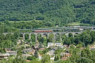Vue générale des viaducs ferroviaire et autoroutiers avec le passage d'un train sur le viaduc ferroviaire.
