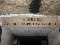 Vue de l'alexandrin du poète Jacques Delille inscrit sur le linteau : Arrête ! C'est ici l'empire de la mort.
