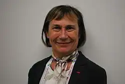 Photo en buste d'une femme souriante portant une veste noire.