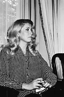 Portrait en noir et blanc de Catherine Deneuve vue de profil et en position assise.
