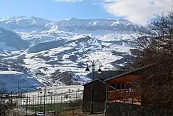 De hautes montagnes enneigées face au lampadaire d'un petit village.