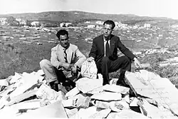 Deux hommes juifs en costume sur des gravats, ils tiennent une pierre sur laquelle on distingue une étoile de David